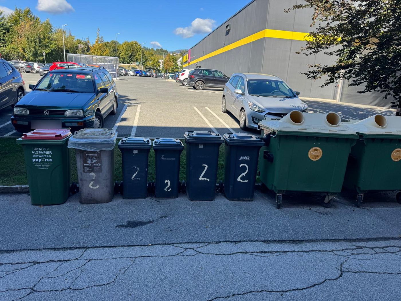 Heute: acht Mülltonnen und Container stehen offen auf der Fahrbahn vor dem Grünstreifen zum BILLA-Parkplatz.