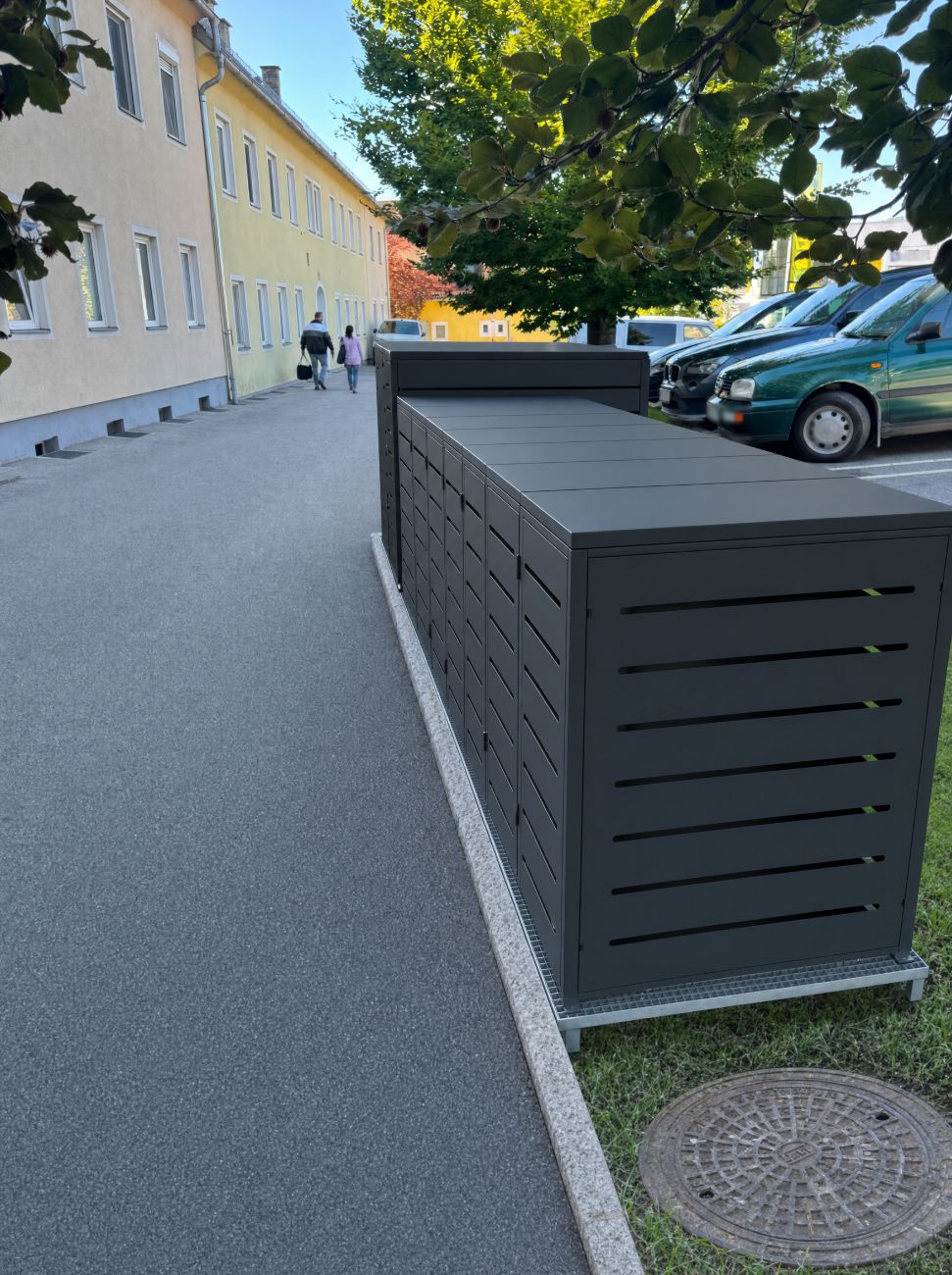 Fotomontage: die Box steht bündig am Randstein im Grünstreifen, der Asphalt ist frei.